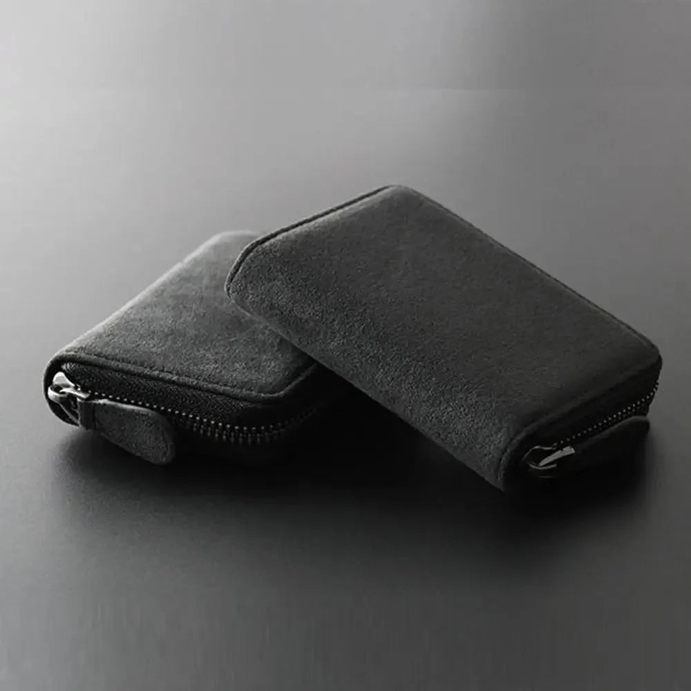 A black compact RFID-blocking card wallet with a zippered closure is shown lying on a dark surface.