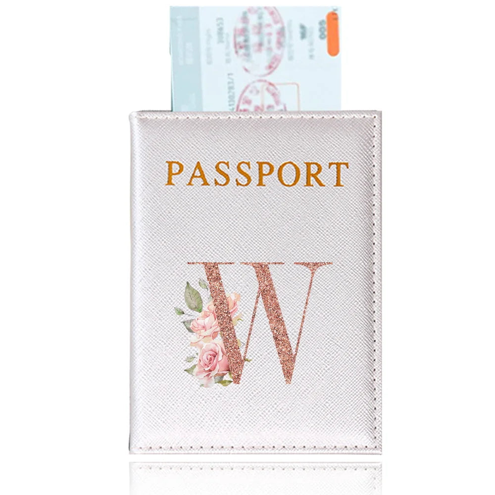 A pink leather passport holder with gold lettering and a rose design, next to an actual passport.