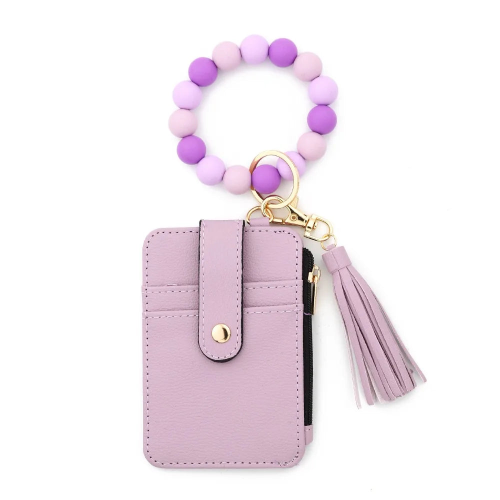 A light purple beaded tassel keychain wristlet with a card holder and pink leather strap.