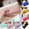 A hand holds a pink quilted wallet with a gold crown buckle and a blue diamond pattern.