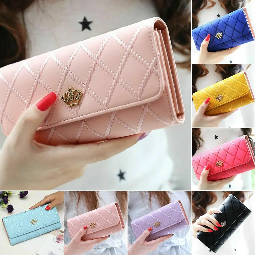 A hand holds a pink quilted wallet with a gold crown buckle and a blue diamond pattern.