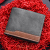 A dark gray PU leather men's wallet with a brown accent, resting on a bed of bright red shredded paper.