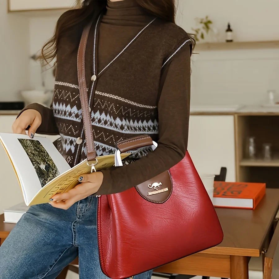 Une femme tient un sac bandoulière vintage en cuir rouge à multiples poches et un carnet dans un intérieur.