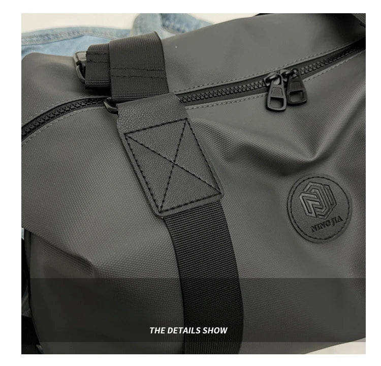 A close-up view of a dark gray Oxford cloth travel tote bag showing stitching and hardware details.