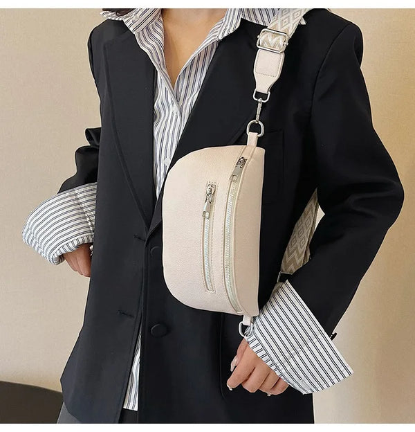 A woman wearing a black blazer and striped shirt holds a cream PU leather multi-pocket crossbody bag.