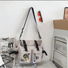 A beige nylon crossbody bag with black straps and orange accents is displayed next to a white storage rack.