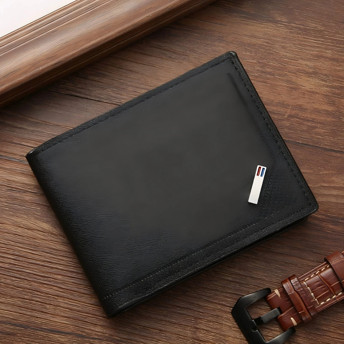 A black slim leather wallet with a money clip resting on a wooden surface.