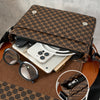 A brown Gucci print flap crossbody bag is shown open, revealing a smartphone and sunglasses on a wooden surface.