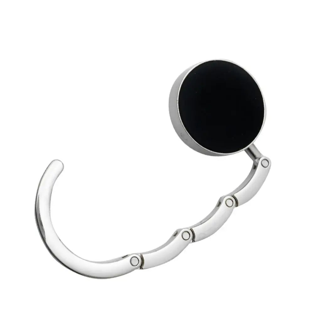 A silver metal desk hook with a black circular loop for hanging bags or garments.
