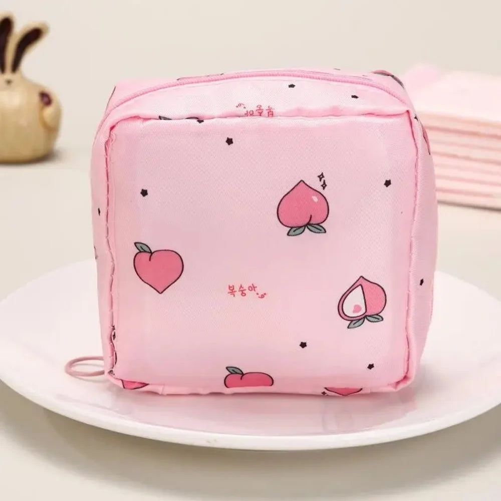 A pink portable waterproof sanitary napkin storage pouch with a repeating pattern of pink hearts and small black dots.