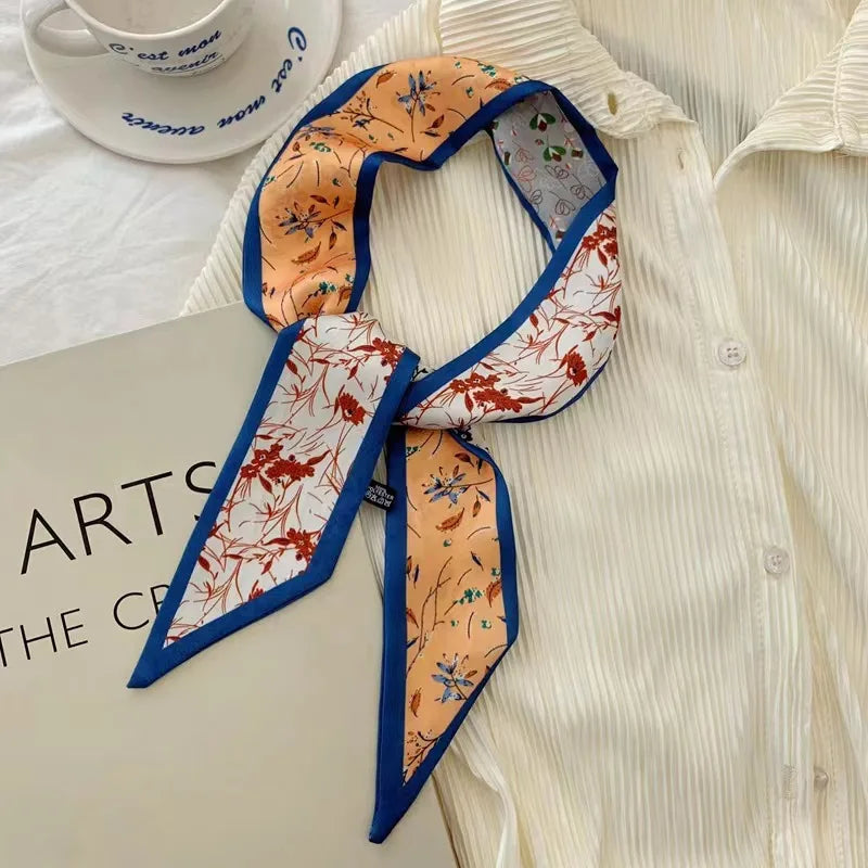 Un foulard floral en soie orange et bleu, noué autour d'une chemise blanche.