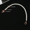 A delicate strand of white pearls with various lengths is displayed against a black background.