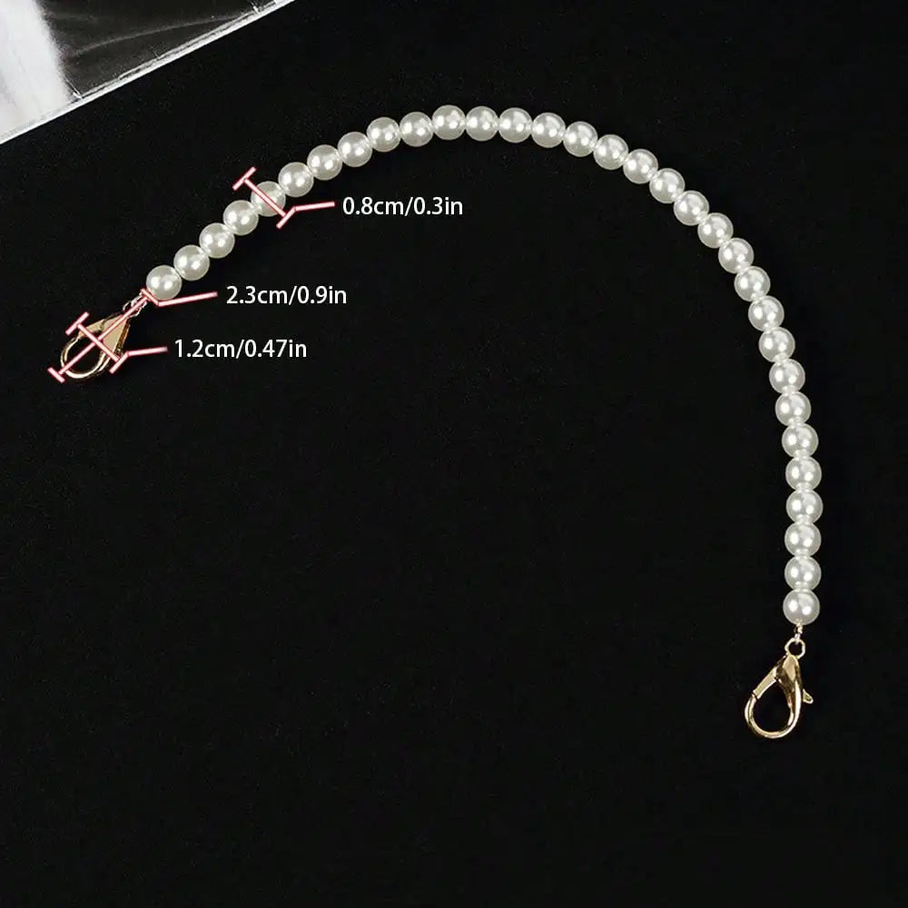 A delicate strand of white pearls with various lengths is displayed against a black background.