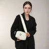 A woman models a white and gray retro M-pattern crossbody bag against a light gray background.