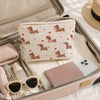 A pink cosmetic bag with a patterned fabric featuring dachshund silhouettes is shown open inside a larger travel organizer.