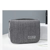 Un sac organisateur portable en tissu gris est posé sur une surface blanche.