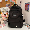A black lightweight nylon college backpack is shown on a white surface with various collectible figures and posters in the ba