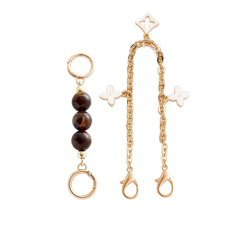 A delicate gold chain featuring a pendant with a marbled dark stone and small floral charms.