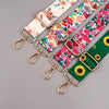 A close-up of a colorful floral patterned strap with gold hardware, used as an adjustable crossbody bag strap.