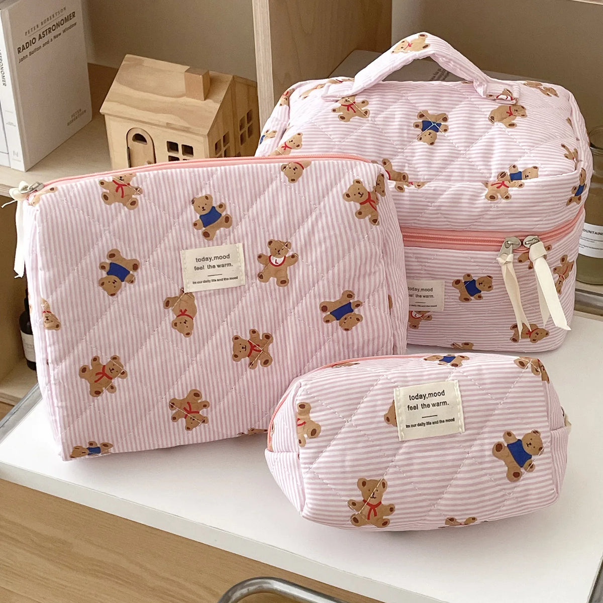 A pink striped bear cosmetic makeup bag with a handle and a matching pouch resting on a white surface.