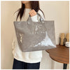 A woman holds a gray transparent waterproof PVC tote bag against a light background.