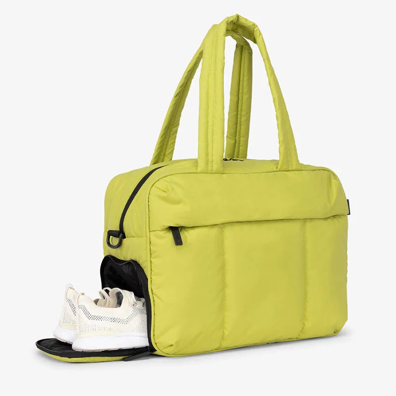 A lime green large capacity women's travel duffle bag with padded straps and a black lining.