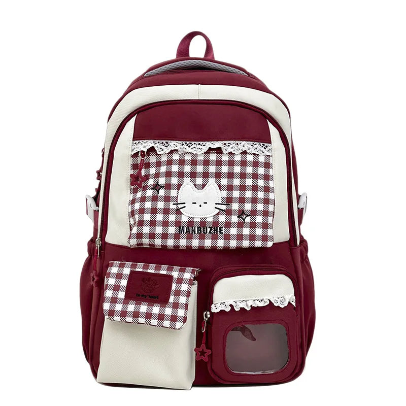 A maroon and white checkered backpack with lace trim and a cat design on the front pocket.