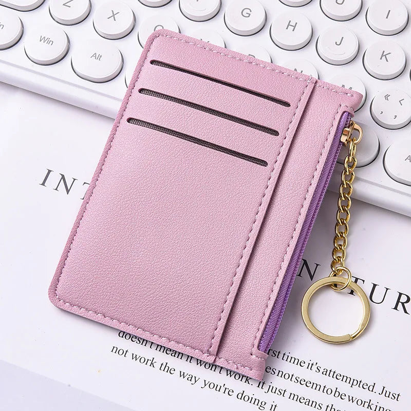 Pinkes Leder-Kartenetui mit lila Reißverschluss auf einer weißen Tastatur.