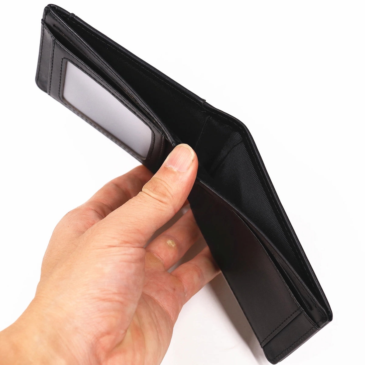 Una mano sostiene una billetera de cuero negro y delgada abierta para mostrar el interior.