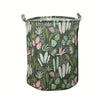 Panier à linge en tissu avec fond vert foncé et motif de feuilles roses et vertes.