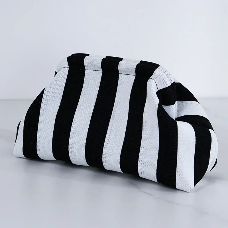 A black and white striped summer crochet handbag is shown lying on a white surface.