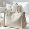 Sac cabas en velours côtelé beige à rayures verticales et petits pois roses sur une surface blanche.
