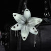 A realistic white orchid flower keychain attached to a black leather handbag.