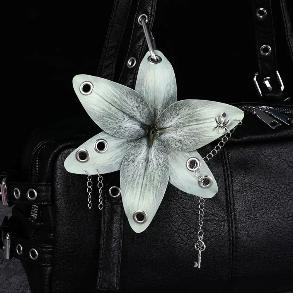 A realistic white orchid flower keychain attached to a black leather handbag.