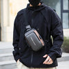 A man wearing a black jacket is holding a black sling chest bag with a phone pocket.