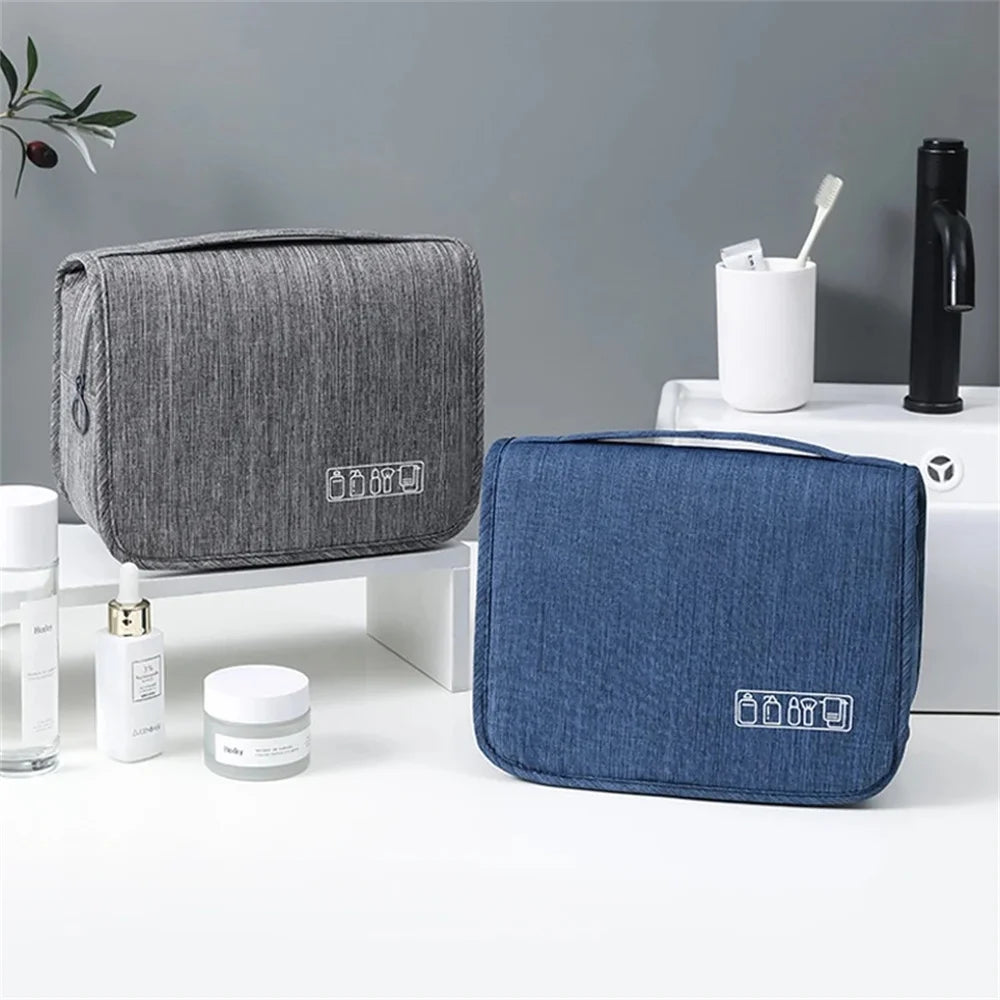 A gray and blue fabric toiletry washbag with a hanging hook is displayed on a white surface.
