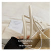 A close-up of a beige straw woven tote bag with light leather trim and matching carrying straps.