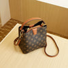 A brown leather bucket bag with a gold zipper and adjustable strap rests on a light wooden surface.