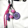 A pink and black fitness keychain featuring a purple weight and a pink box attached to a white leather bag.