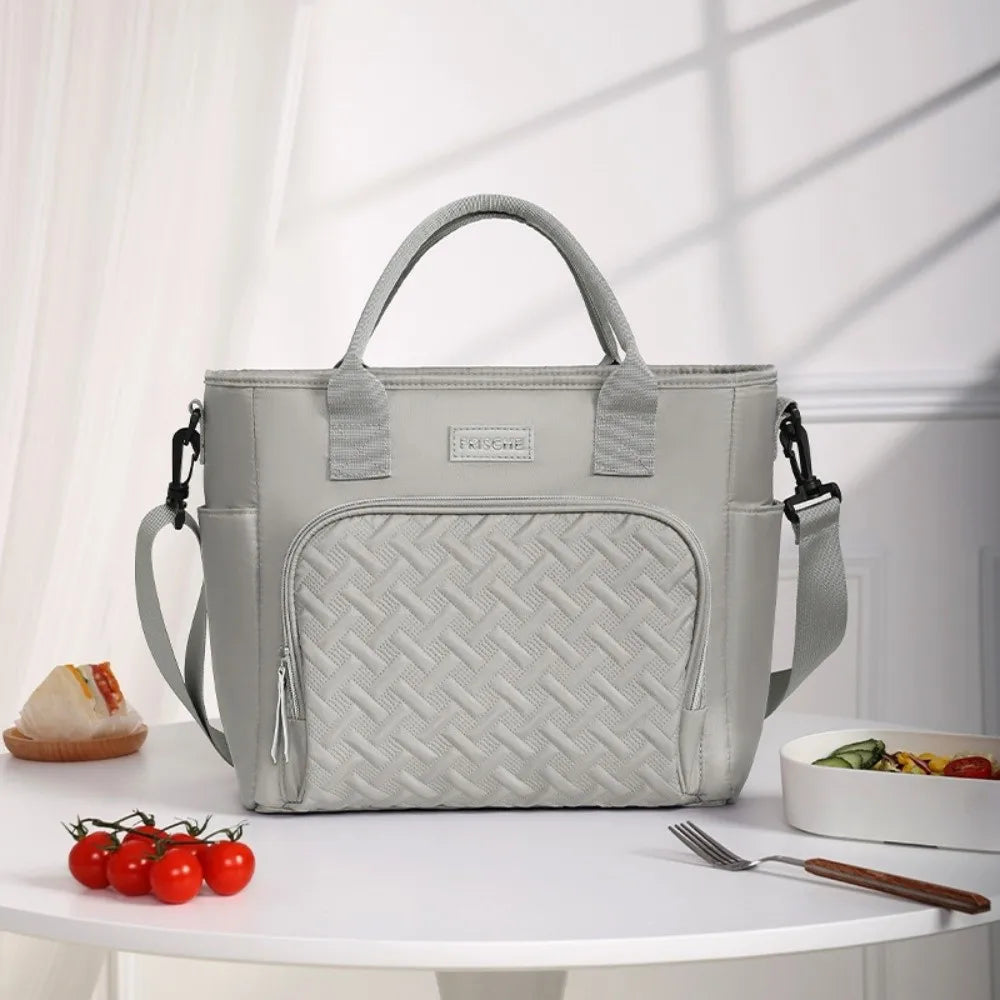 A light gray durable insulated lunch bag with a woven pattern sits on a white table.