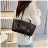 A woman is holding a dark brown classic PU leather tote bag with gold hardware against a light background.
