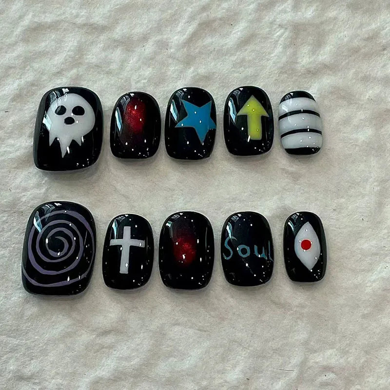 A set of 10 black acrylic press-on nails featuring various designs including a skull, stars, arrows, and spiritual symbols.