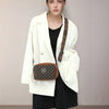 A woman models a white blazer and black outfit with a brown patterned crossbody bag.
