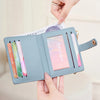 A light blue minimalist wallet is shown being held by hands, displaying various cards and IDs.