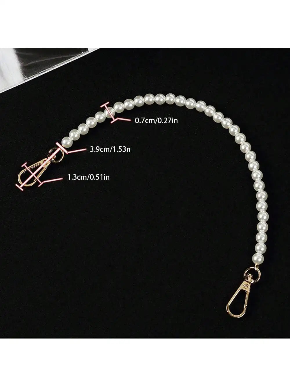 A close-up of an elegant pearl strap for handbags showing various measurements and a gold clasp.