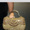 A golden diamond rhinestone evening clutch bag with a tassel being held by a person's hand.