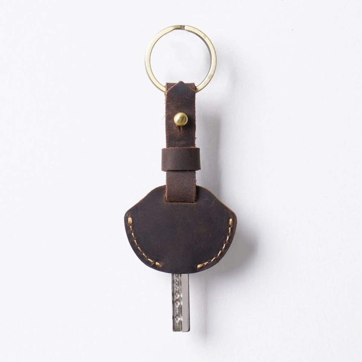 A brown leather key fob cover with a metal ring and a key attached.
