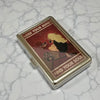 A vintage snap metal card holder with a red and gold design featuring text that says Lose Your Mind and Find Your Soul.
