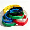 Une pile de bracelets en silicone colorés jaune, noir, bleu, vert, rouge et blanc.