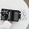 Black polka dot passport holder with multiple card slots and an attached white patterned pouch